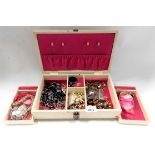 A cream leatherette jewellery box and contents of costume jewellery, comprising dress rings, butterf