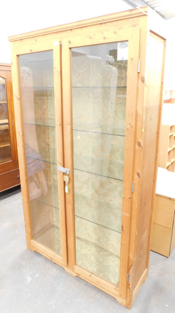 A pine display cabinet, fitted with four glass shelves, on a moulded base, 195cm high, 114cm wide, 4