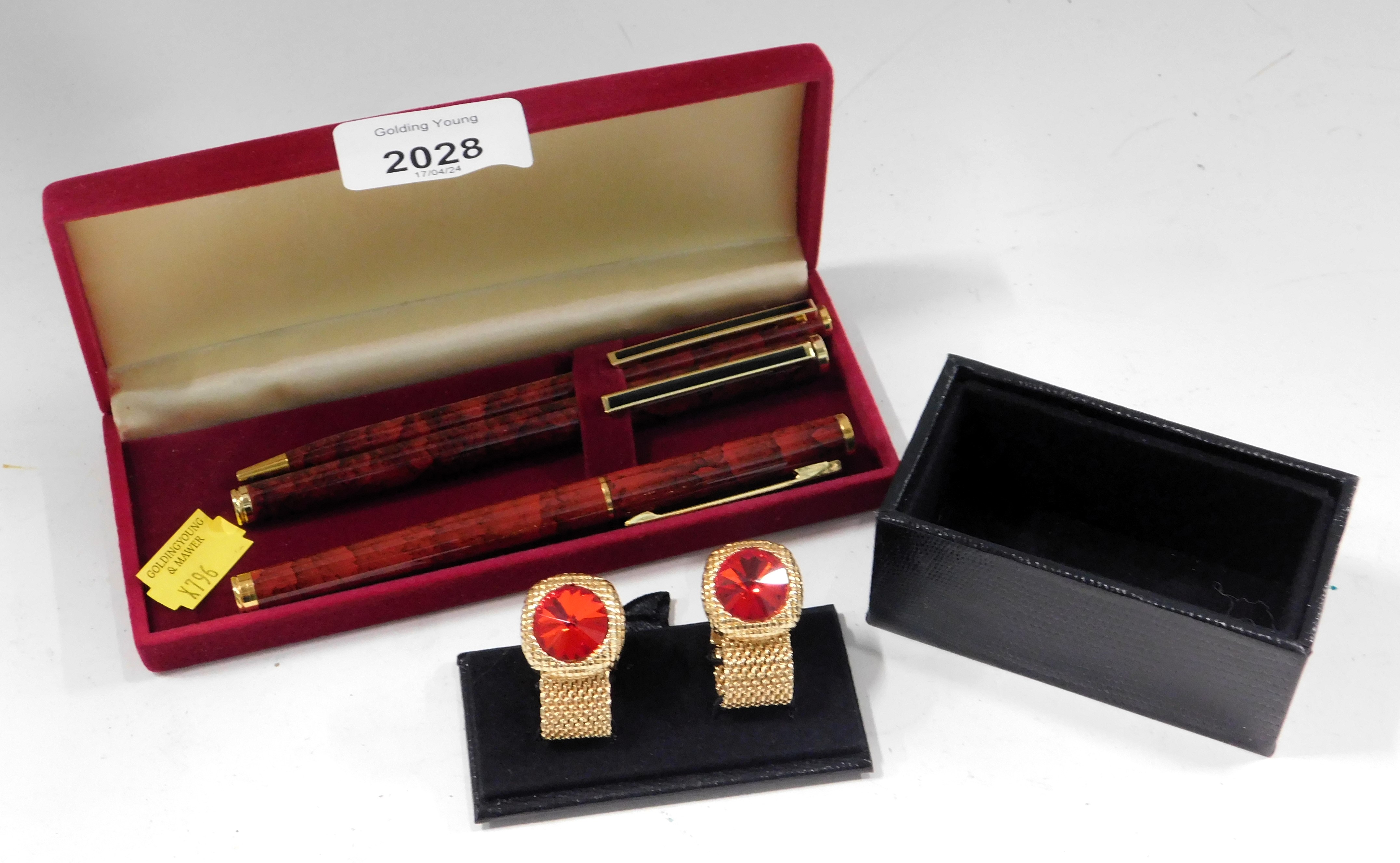 A cased set of three red mottled finish ball point pens, and a small group of plated and gold finish
