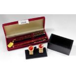 A cased set of three red mottled finish ball point pens, and a small group of plated and gold finish