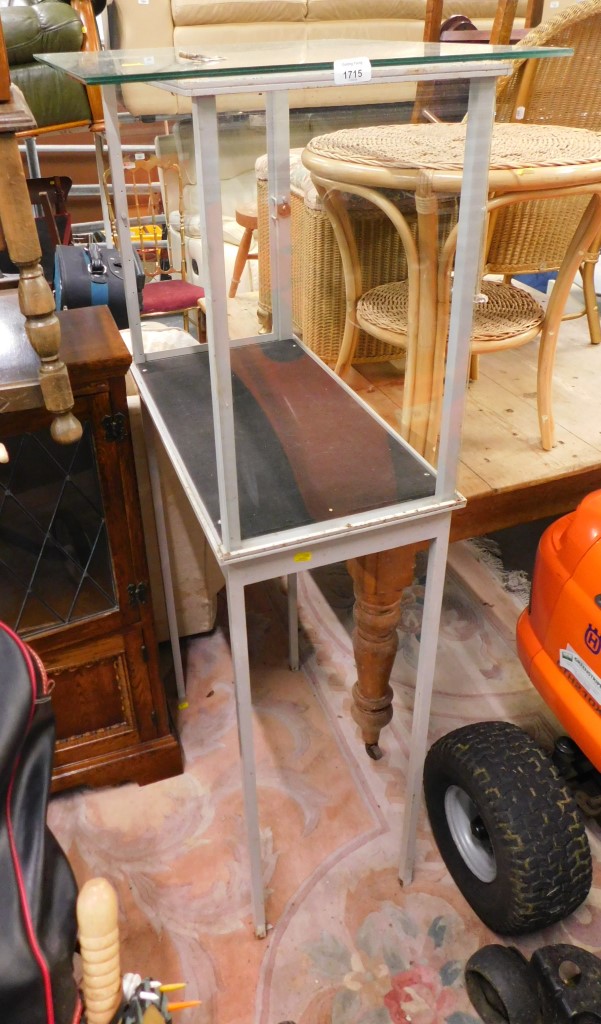 A grey painted metal glass display case, on tapered legs.