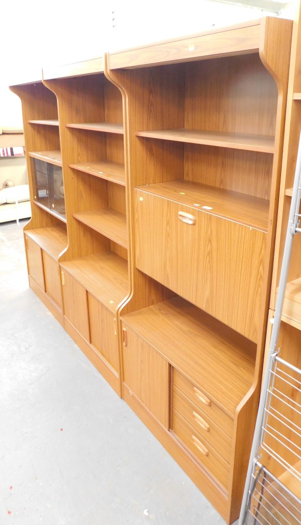 A retro style teak wall unit, in three sections to include cupboard top, cocktail cabinet and cupboa