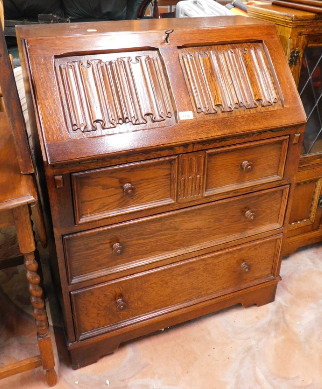 An oak bureau, with linenfold top opening to reveal fitted interior above two short and two long dra