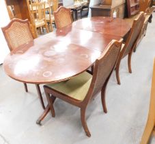 A reproduction mahogany twin pedestal dining table, with additional leaf and four cane backed chairs