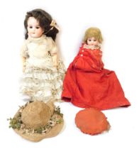 A collection of bisque headed dolls, comprising one in red dress with brown fixed eyes and teeth, on