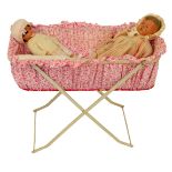 An early 20thC doll's crib, on a cream painted metal base, with floral surround, and two doll's, to