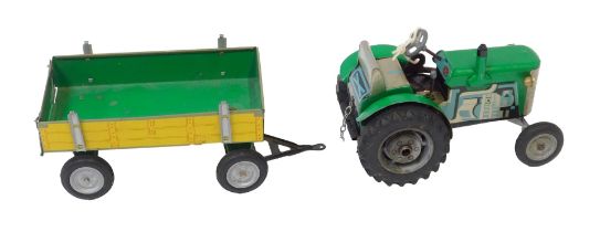 A modern tinplate clockwork tractor and trailer set, with key, painted in green with yellow trailer.