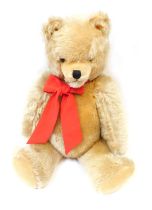 A 19thC plush blonde jointed teddy bear, with wire wool filling and pad paws, with red bow, 51cm hig