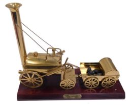 A brass model of Stephenson's Rocket, on a mahogany plinth.