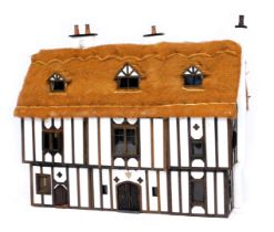 A three storey substantial Tudor style doll's house, with three chimneys, thatched roof, in painted