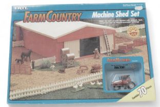 An Ertl Farm Country Machine Shed set, with farm machines, tractor, boxed.