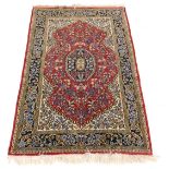 A Persian style rug, decorated with flowers and leaves, on a red ground within a cartouche, with cre