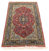 A Persian style rug, decorated with flowers and leaves, on a red ground within a cartouche, with cre