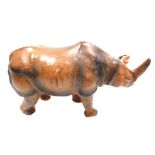 A vintage Liberty style leather bound wooden figure of a rhinoceros, with inset black eyes, 50cm wid