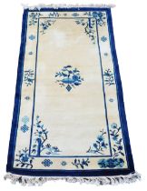 A Chinese blue and cream ground rug, decorated with flowers and blossom, 187cm x 94cm.