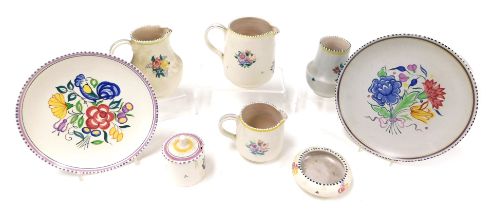 A group of 20thC Poole pottery, traditionally decorated with flowers, comprising three jugs, two pla