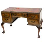 A walnut desk, the break front top with three red and gilt tooled leather insets, surrounded by a le