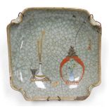 An early 20thC Chinese ge-type dish, of curved, square form, over painted with a vase of peacock fea