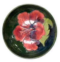 A Moorcroft pottery Hibiscus pattern bowl, green ground, impressed marks and paper label, 14cm wide.