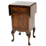A walnut side cabinet, the rectangular cross banded top with two drop leaves, above a drawer and two