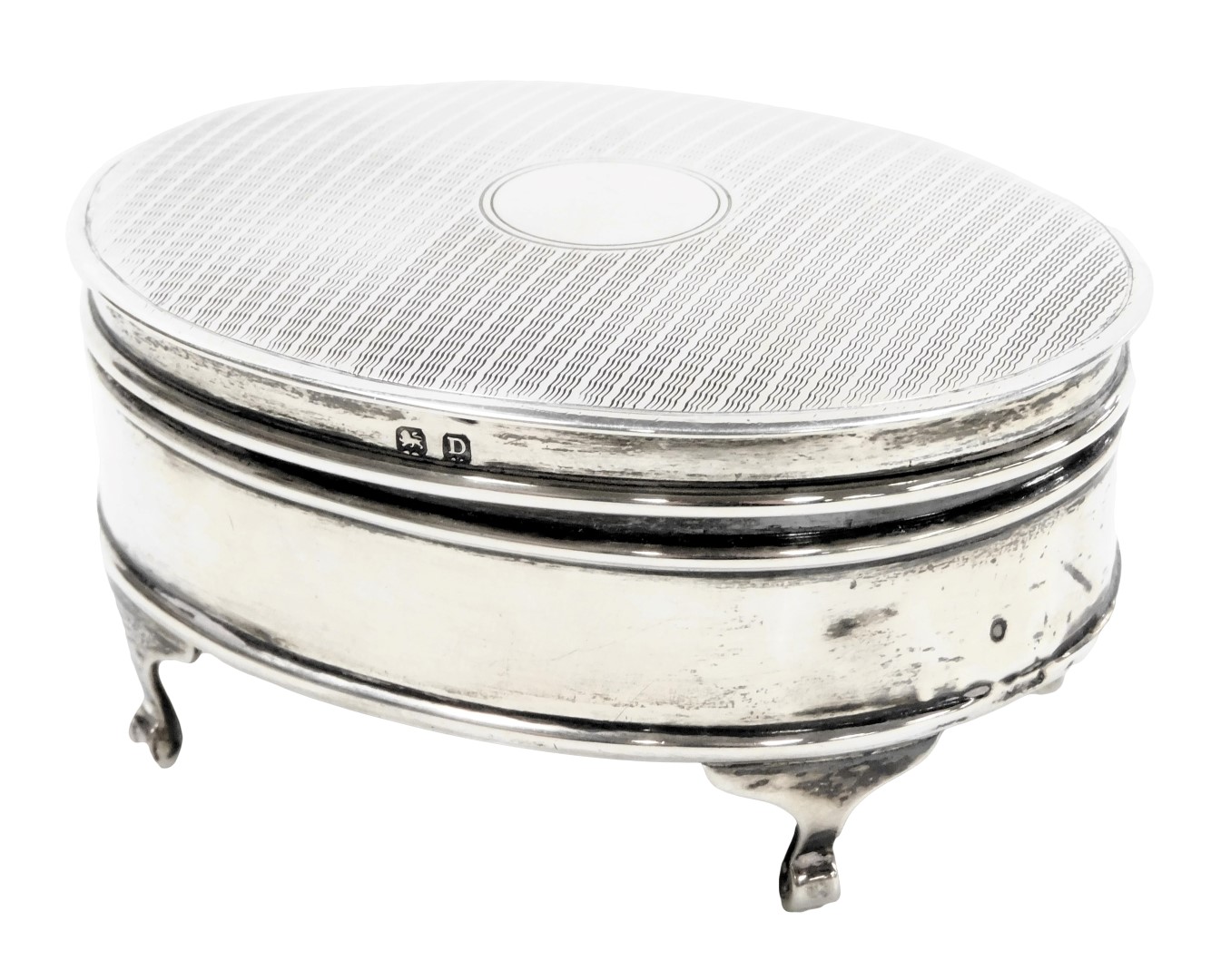 A George V silver oval dressing table box, with engine turned decoration, vacant circular reserve, r