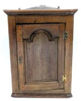 An 18thC oak hanging corner cupboard, with a single panelled door and brass H shaped hinges, 93cm hi