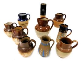 A group of Doulton Lambeth and other stoneware two tone harvest jugs, a chine decorated jug, sprig m