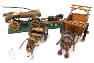 Three pottery cart horses, with wooden carts, one for tree trunk carrying, on a green rectangular ba