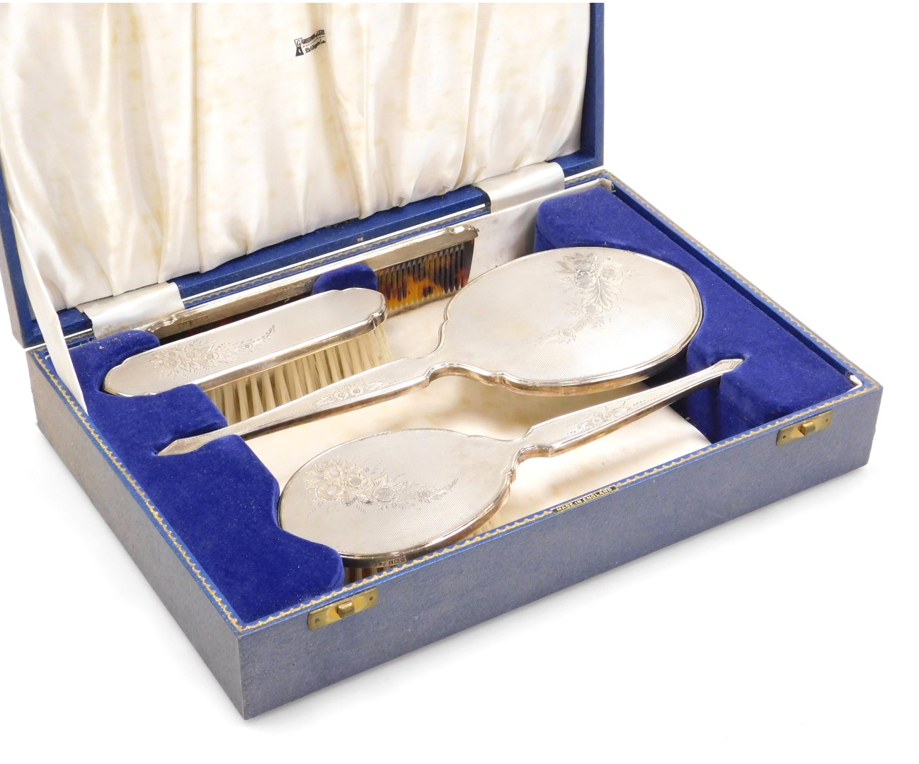 An Elizabeth II four piece silver backed dressing table set, with engine turned and engraved floral