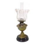 An early 20thC brass oil lamp, raised on a glass socle, with glass chimney and floral etched frilled