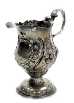 A George III silver cream jug with a later loaded base, of baluster form, embossed with flowers, cir