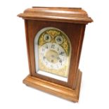 An early 20thC oak cased mantel clock, domed brass dial with foliate spandrels, circular silver chap