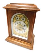 An early 20thC oak cased mantel clock, domed brass dial with foliate spandrels, circular silver chap