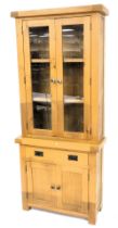 A light oak cabinet, the top with two glazed doors, the base with a drawer and two panelled doors, o