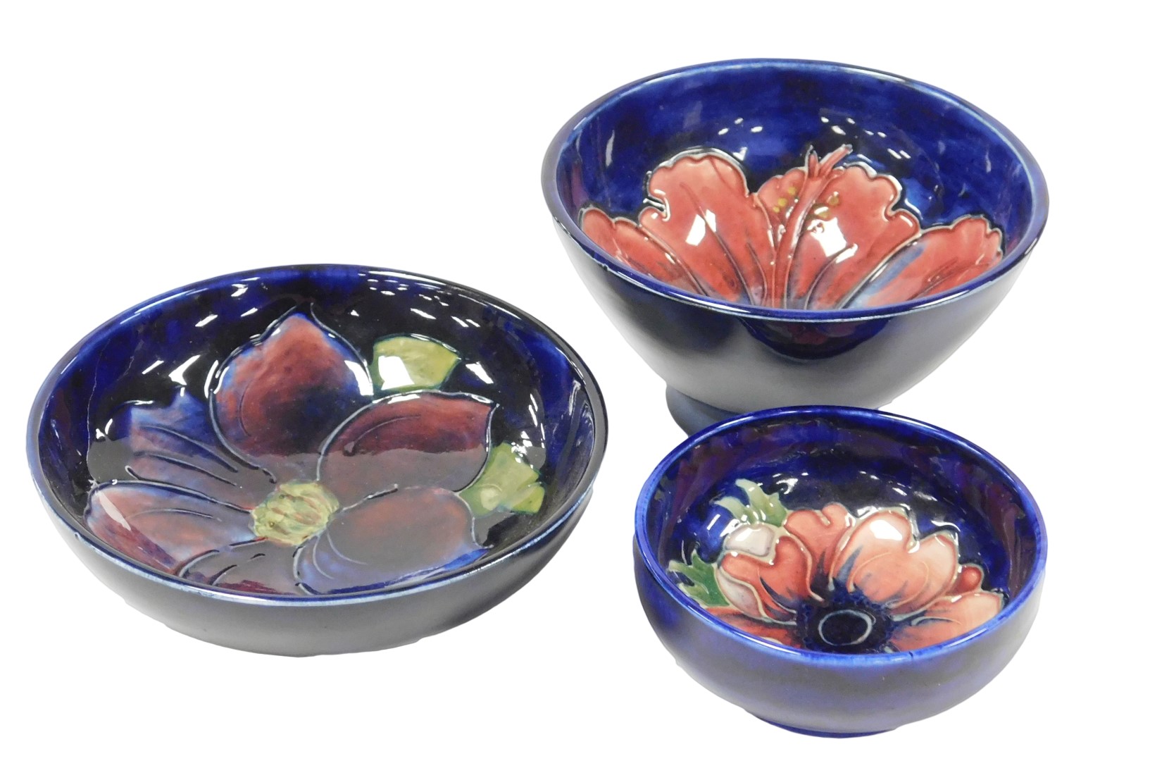 A group of Moorcroft pottery, comprising three bowls decorated in the Hibiscus, Clematis and Anemone