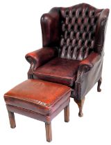 A oxblood red leather upholstered wing back Chesterfield armchair, in George III style with studded