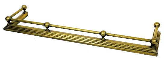 An early 20thC brass fire curb or fender, with tubular rail and fluted tapering base, 133cm wide.