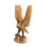 A wooden carved figure of an eagle, its wings aloft, raised on a naturalistic base, 78cm high.
