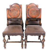 A set of four oak dining chairs, each with a brown leather back, embossed with a rose, within brass