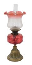 A late 19thC Young's brass oil lamp, with a cranberry glass reservoir, glass chimney and frosted to