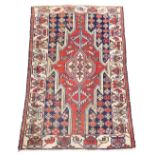 A Persian Kazak style rug, with a design of multicoloured geometric devices, one wide and one narrow