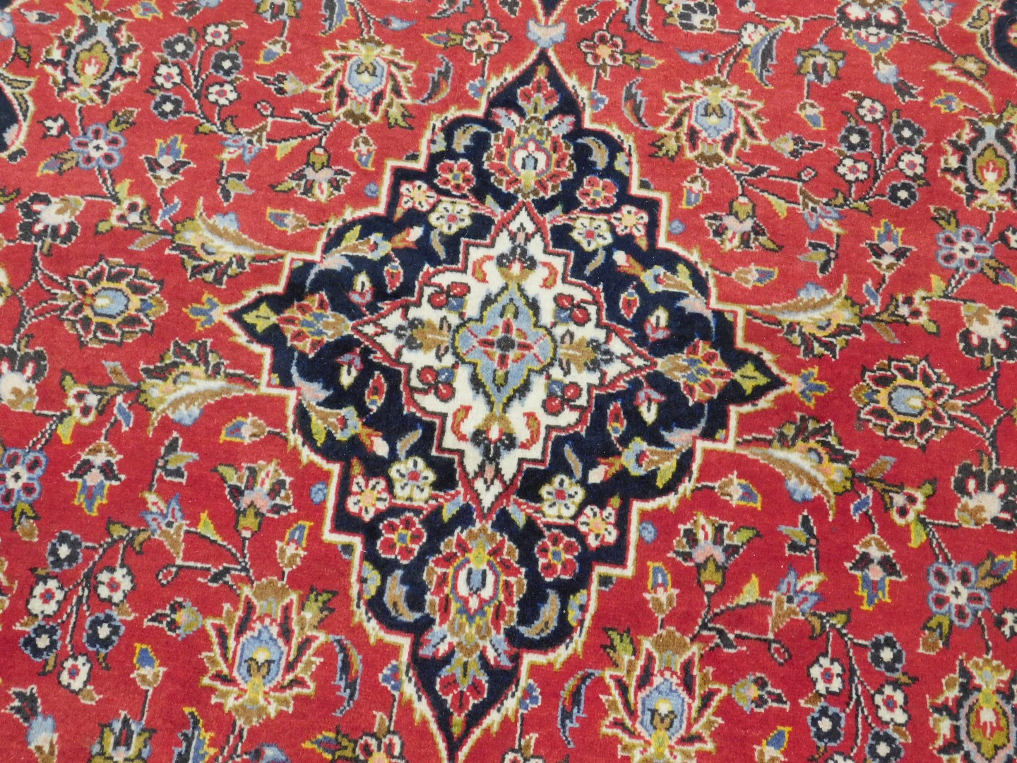 A Persian rug decorated with leaves and scrolls, on a red ground, with one wide and two narrow borde - Image 2 of 3
