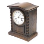 An early 20thC oak cased mantel clock, circular enamel dial bearing Roman numerals, eight day moveme