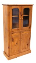 A pine side cabinet, the top with a moulded edge above two glazed doors, a slide and two panelled do