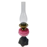 A late 19thC Young's number two cast iron oil lamp, with a pink opaline glass reservoir, moulded wit