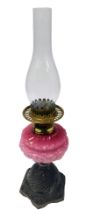 A late 19thC Young's number two cast iron oil lamp, with a pink opaline glass reservoir, moulded wit