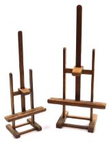 A pair of graduated oak table easels, 35cm and 43cm high.