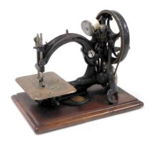 A late 19thC Wilcox and Gibbs sewing machine, raised on a wooden base.