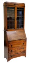 An oak bureau bookcase, topped with two leaded glazed doors, above a fall enclosing a partially fitt