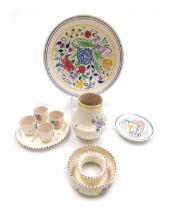 A group of 20thC Poole pottery, traditionally painted with flowers, comprising four egg cups on stan